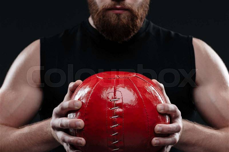 Cropped image of trainer with ball. holding ball in hands. isolated dark background, stock photo