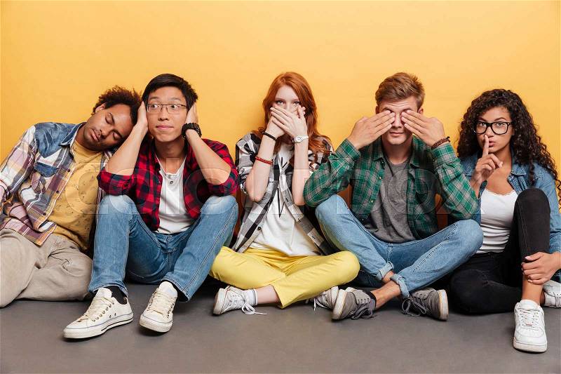 Group of amusing playful young people covered eyes, ears and mouth over yellow background, stock photo