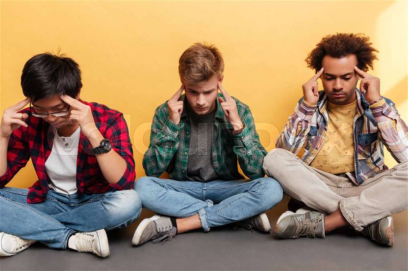 Three sad unhappy young men friends touching temples and having headache over yellow background, stock photo