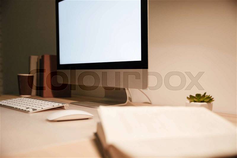 Modern computer with blank screen monitor on the table in the evening, stock photo