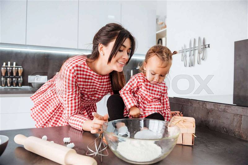 Child and mom in dresses on kitchen. cooked, stock photo