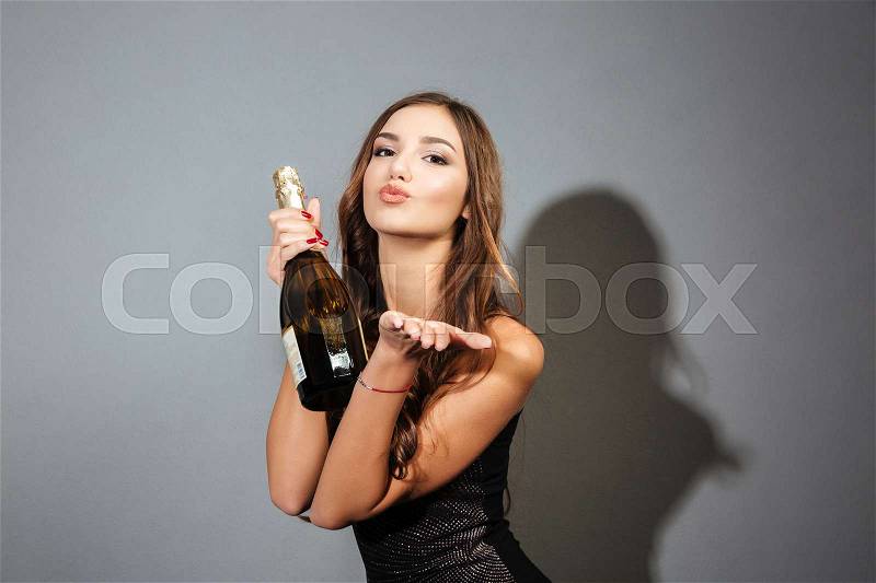 Model sends air kiss. with bottle. gray background, stock photo