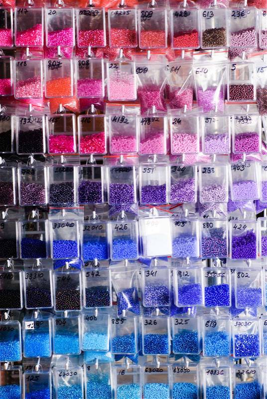 Colorfull glass beads batches in plastic bags for beadwork in craft shop, stock photo