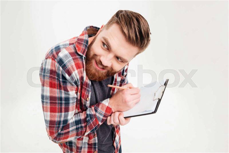 Portrait of a funny bearded man making funny face while writing in clipboard isolated on a white background, stock photo
