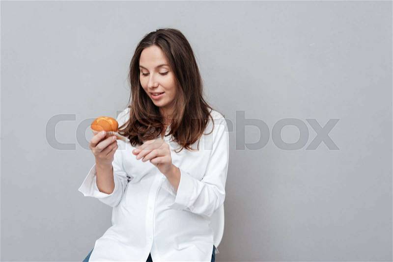 Pregnant woman with cake. isolated gray background, stock photo