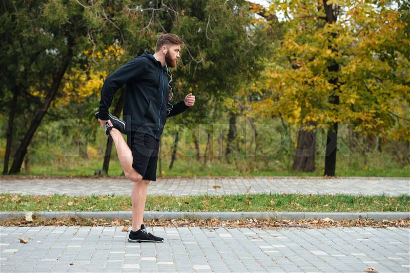 Full length runner warming up in park, stock photo