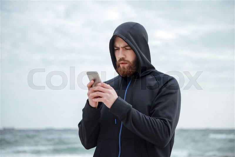 Runner with phone on beach. looking at phone, stock photo