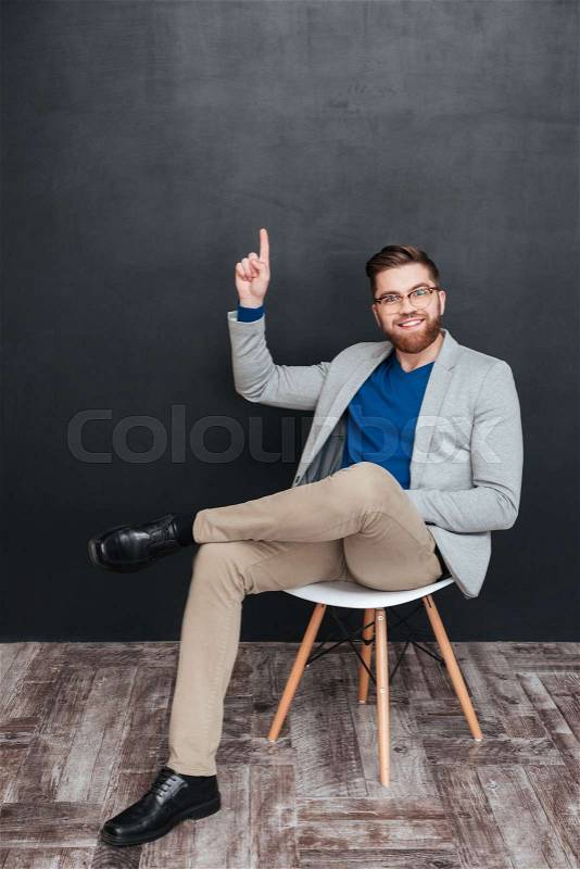 Man sitting on a chair. full length portrait. showing finger up, stock photo
