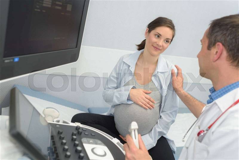 Doctor showing pregant woman ultrasound, stock photo