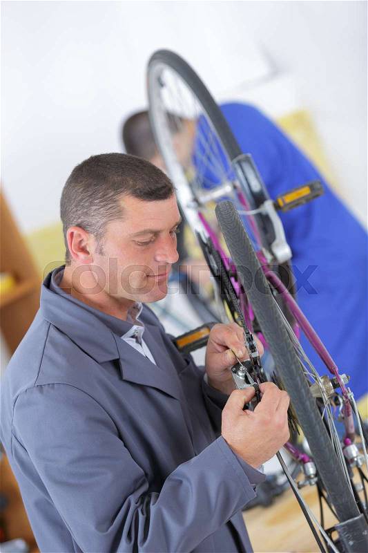 Stylish bicycle mechanic doing his professional work in workshop, stock photo