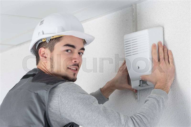 Technician checks burglar alarm in professional building, stock photo
