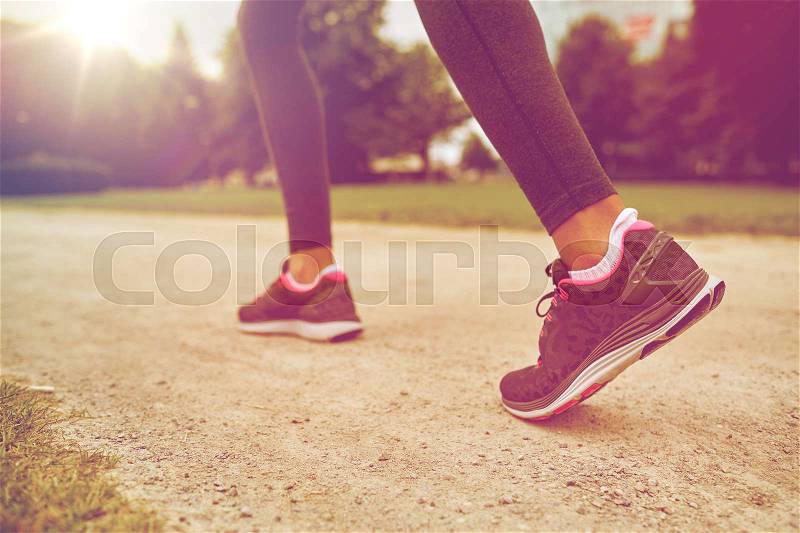 Fitness, sport, training, people and lifestyle concept - close up of woman feet running on track from back, stock photo