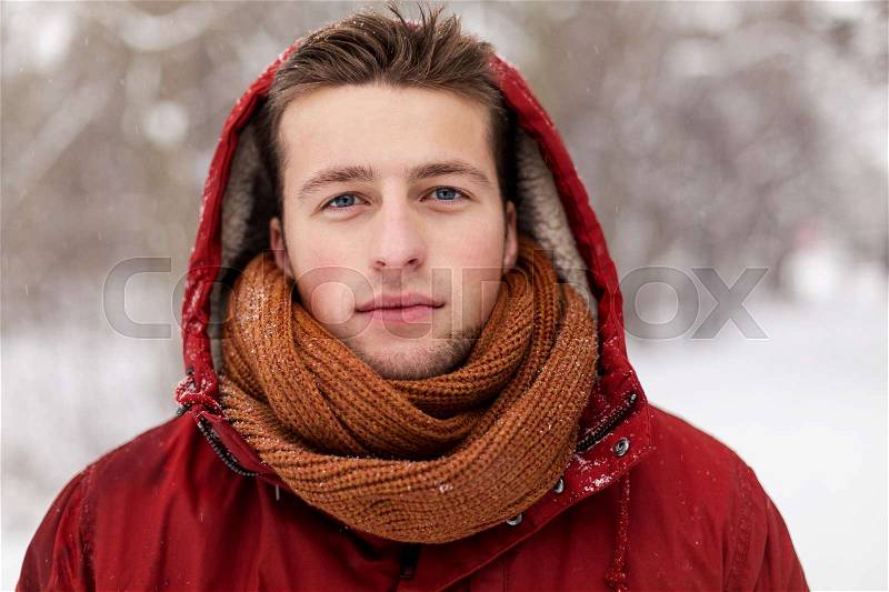 People, christmas, winter and season concept - happy man in hood and scarf outdoors, stock photo