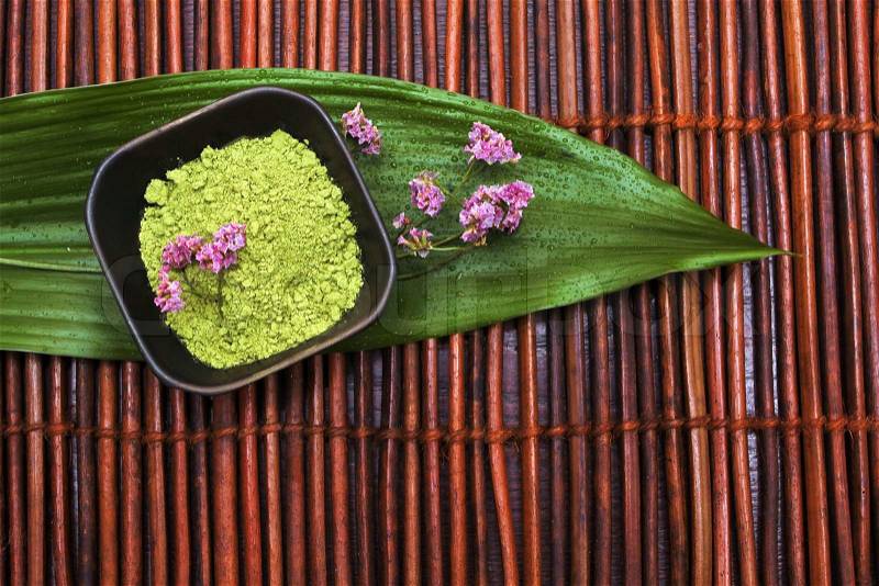 Green spa mud, violet flower and leaf on brown mat, stock photo