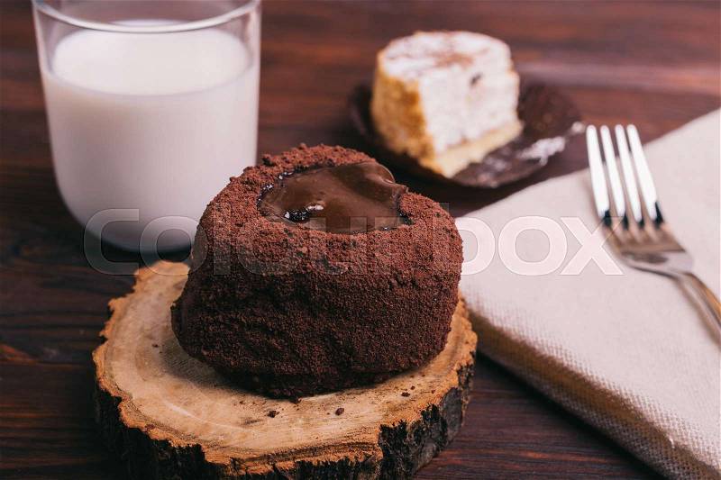 Glass of milk, cakes and fork on brown table, stock photo