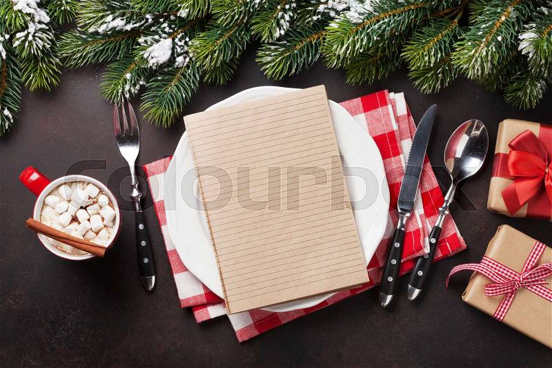 Christmas dinner plate, silverware, fir tree, gift box, hot chocolate. Top view with notepad for your recipe, stock photo