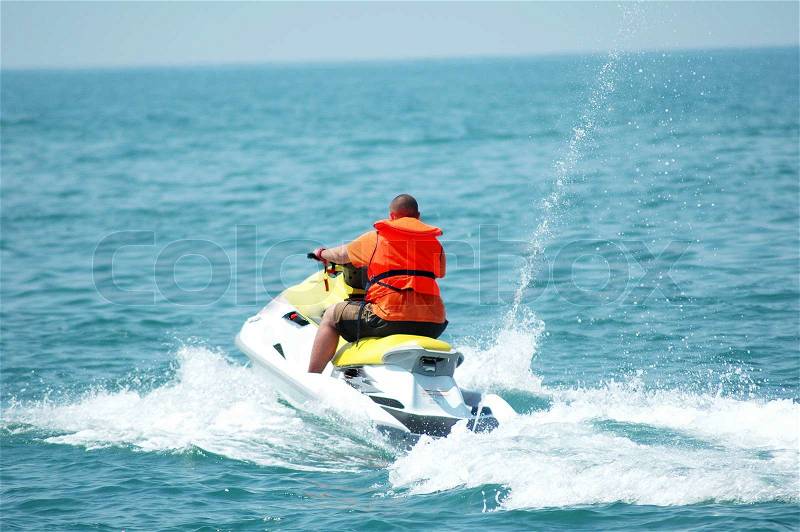 Man driving a motorised scooter at sea, stock photo