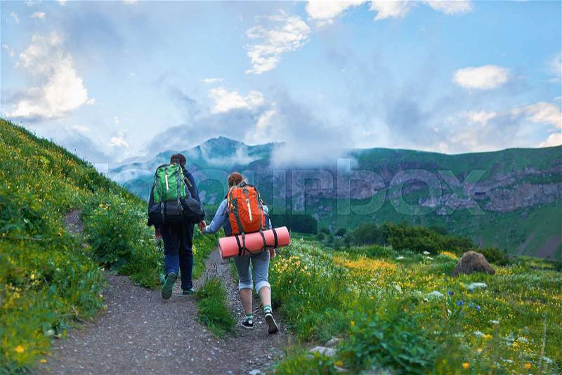 Couple with backpacks going to hike, climb the mountain along a path, stock photo
