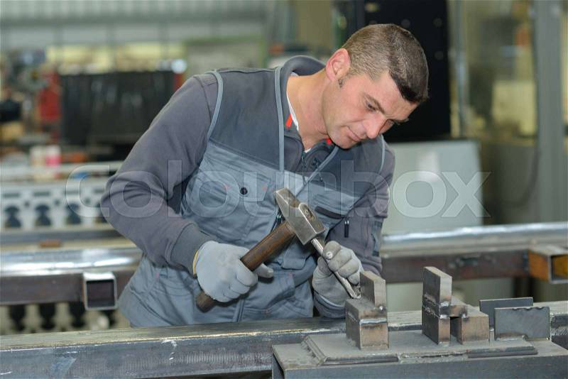 Worker doing metal work in factory, stock photo