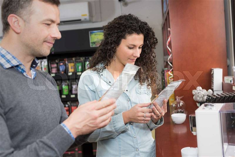 Man and woman by vending machine reading packet, stock photo
