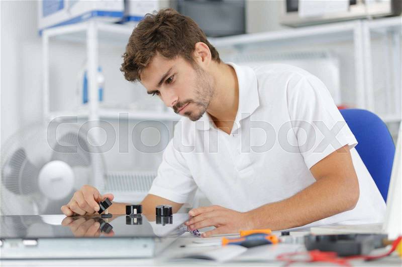 Young repairman installing induction cooker in kitchen, stock photo