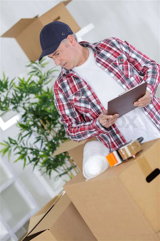 Middle age man packing cardboard box with sellotape, stock photo