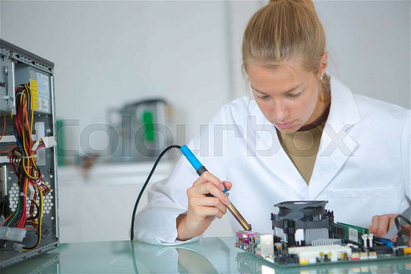 Girl with a tester and a printed circuit board, stock photo