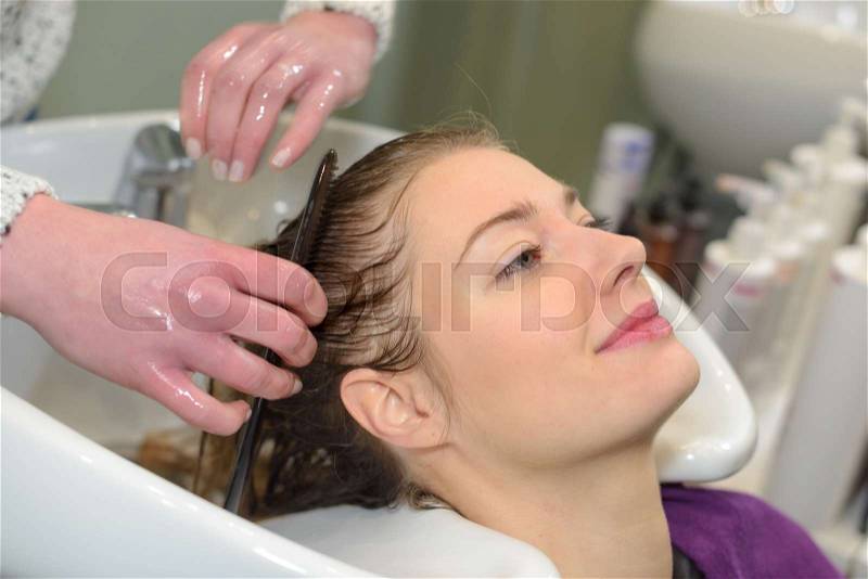 Woman washing head in hair salon, stock photo