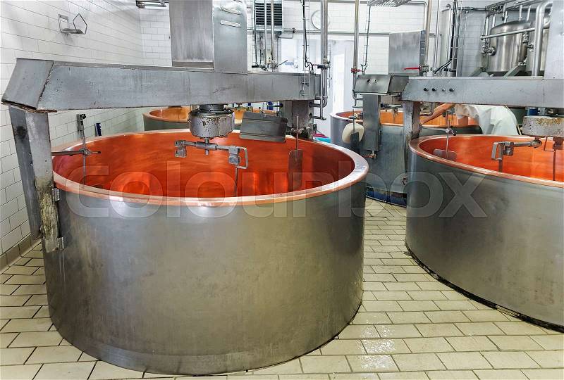 Empty tanks for Processing of Gruyere de Comte Cheese in the dairy in Franche Comte, Burgundy, in France. Cheesemaker on the background, stock photo
