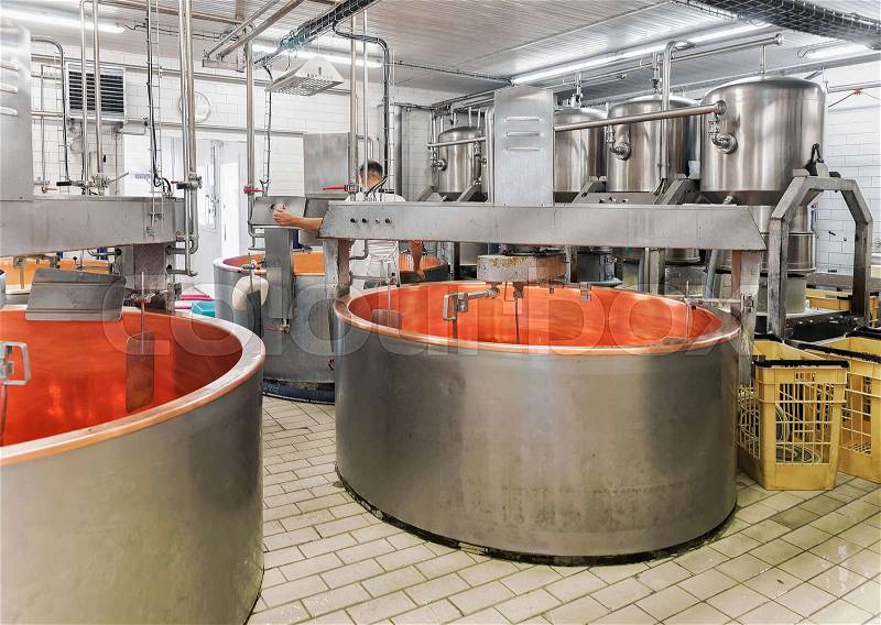 Empty tanks for Processing of Gruyere de Comte Cheese at the dairy in Franche Comte, Burgundy, in France. Cheesemaker on the background, stock photo