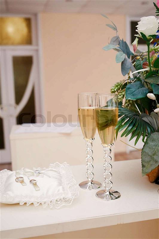 Two glasses of champagne and pillow with rings on the table for wedding ceremony, stock photo