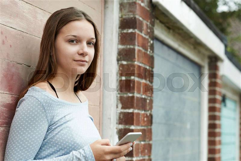 Teenage Girl Texting On Mobile Phone In Urban Setting, stock photo