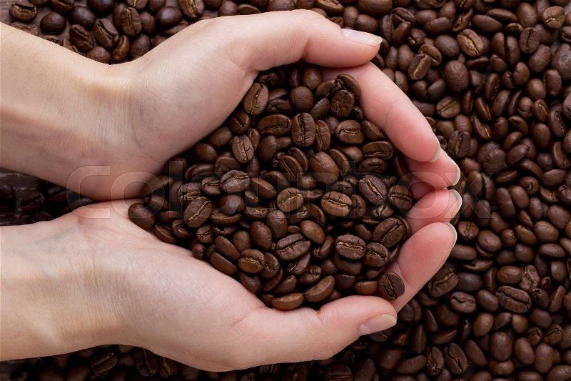 The handful of high-quality coffee beans in hands of a young man, stock photo