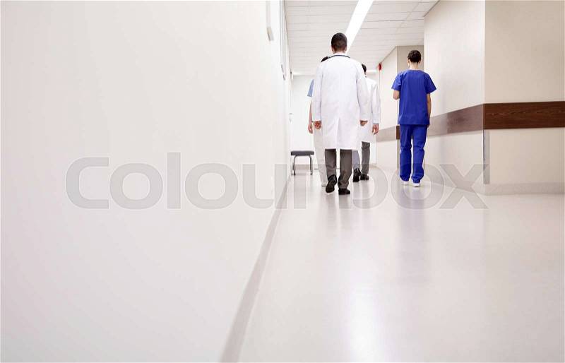 Clinic, profession, people, healthcare and medicine concept - group of medics or doctors walking along hospital corridor, stock photo