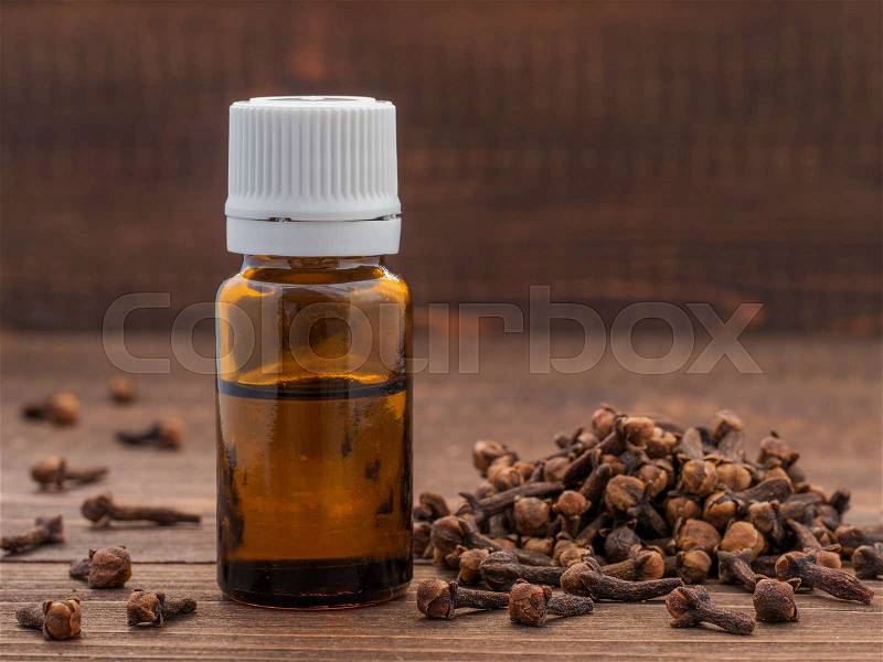 Spice clove essential oil in dark glass bottle anddry cloves on dark wooden background with copy space, stock photo