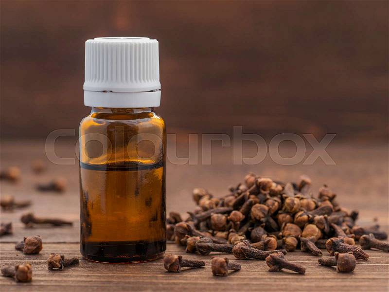 Spice clove essential oil in dark glass bottle anddry cloves on dark wooden background with copy space, stock photo