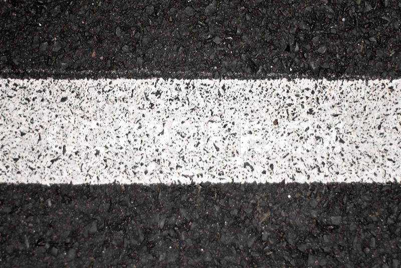 Closeup of a tar or asphalt pavement texture with a white line painted down the center, stock photo