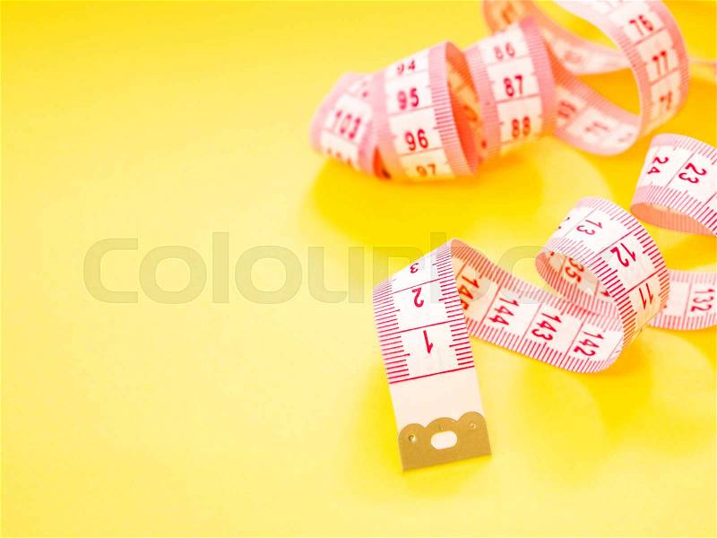 Red and white measuring tape on yellow background, stock photo