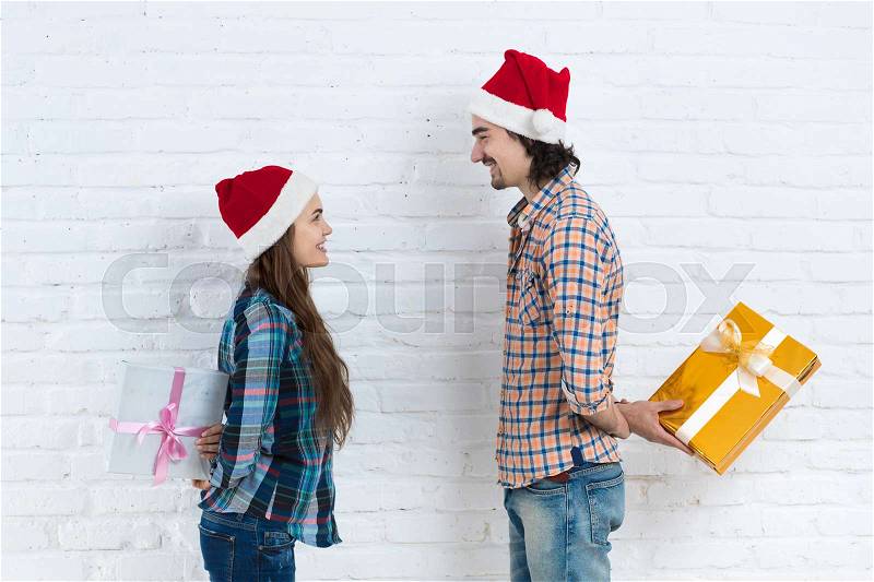 Christmas Holiday Happy Couple Hold Surprise Present Boxes Wear New Year Santa Hat Cap, Man And Woman Smiling Over White Brick Wall, stock photo