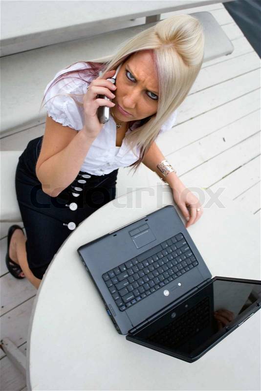 A beautiful young woman in a mobile business setting with her cell phone and laptop, stock photo