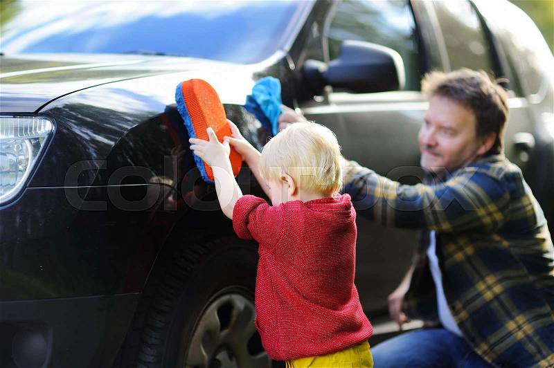 Middle age father with his toddler son washing car together outdoors, stock photo