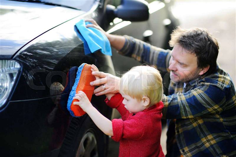 Middle age father with his toddler son washing car together outdoors, stock photo