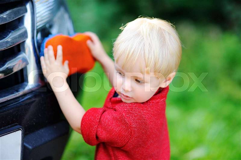 Cute toddler son playing washing fathers\'s car outdoors, stock photo