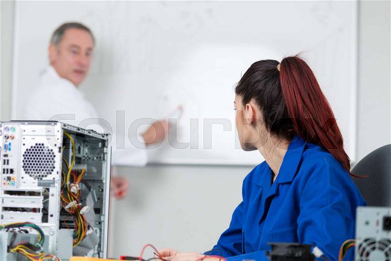 Teacher showing student on whiteboard how to fix a computer, stock photo