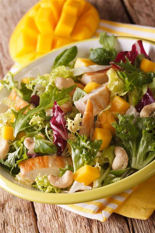 Fresh salad with grilled chicken, mango, arugula, lettuce, spinach and chicory close-up on the table. vertical\, stock photo