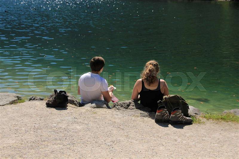 The couple, boy and girl have a break and have a beautiful view over the lake in the wonderful summer, stock photo