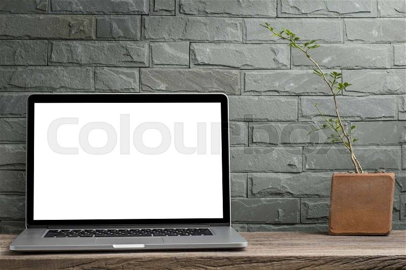 Laptop blank screen on old wooden desk wall bricks background, stock photo