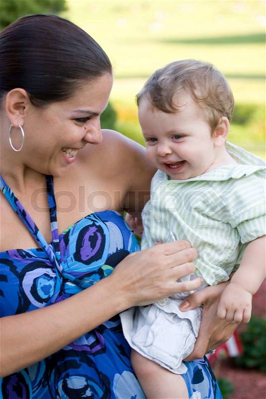 A young mother tickles her baby happily, stock photo