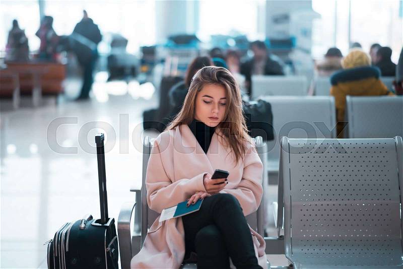 Airport business woman waiting in terminal. Air travel concept with casual businesswoman sitting with suitcase. Mixed race female professions, stock photo