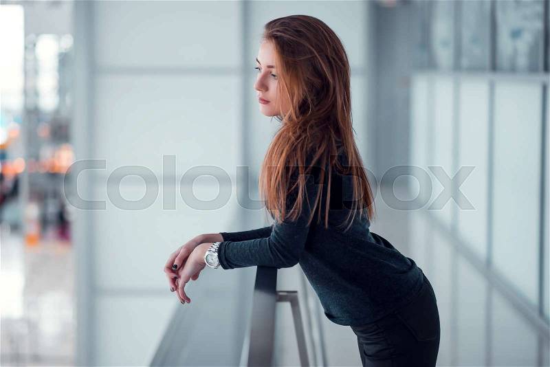 Beautiful young female posing on glazed balcony. Airport at the background, stock photo
